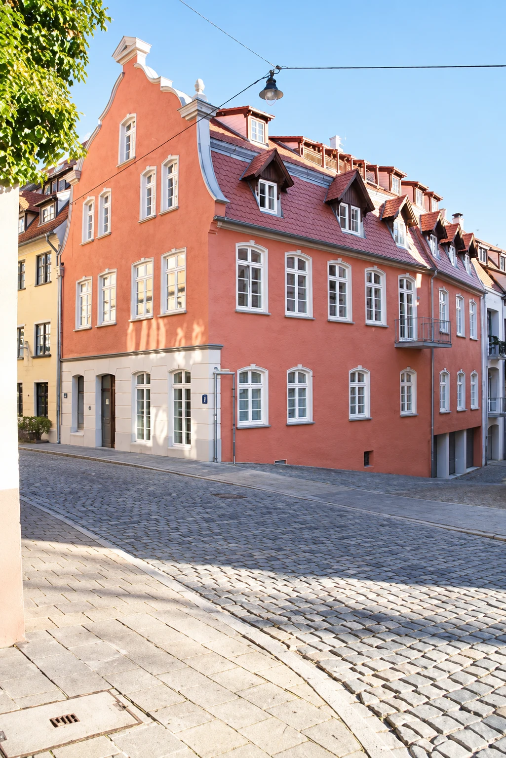 Historisches Eckhaus mit rosafarbener Fassade und weißen Sprossenfenstern
